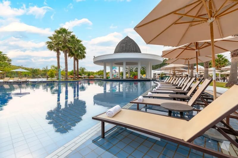 Piscina do Jardins de Jurema com espreguiçadeiras, guarda-sóis e quiosque de cúpula ao fundo